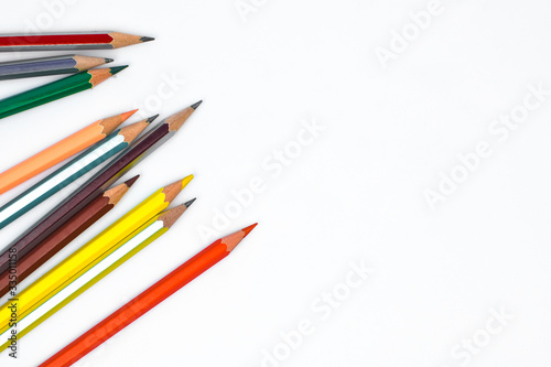 Scattered row of various colored wood pencil crayons arranged together in a line format