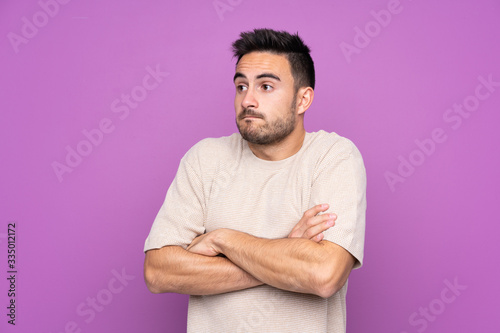 Young handsome man over isolated purple background making doubts gesture while lifting the shoulders