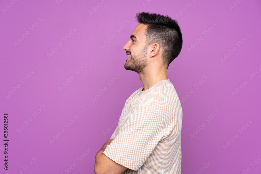 Young handsome man over isolated purple background in lateral position Young handsome man over isolated purple background in lateral position
