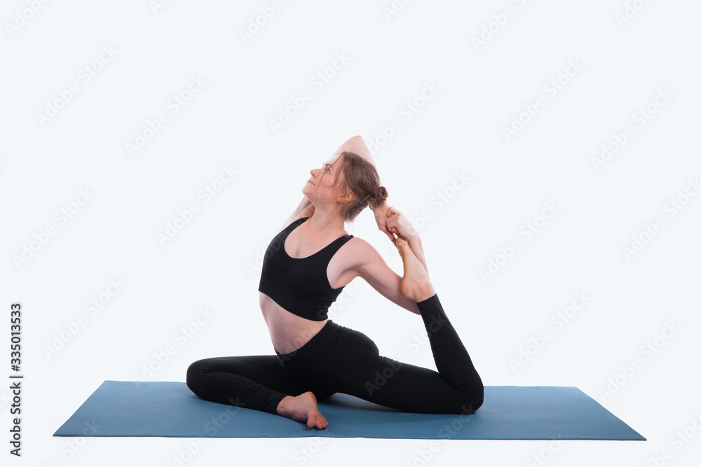 Photo of young sport woman doing yoga on mat over white background in studio
