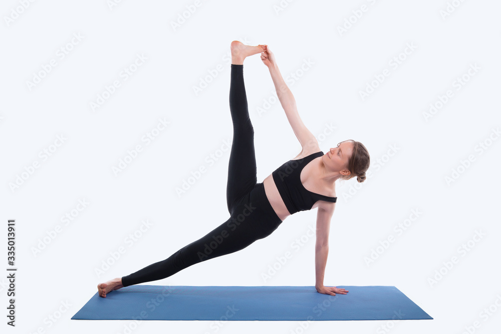 Photo of young sport woman doing yoga on mat over white background in studio