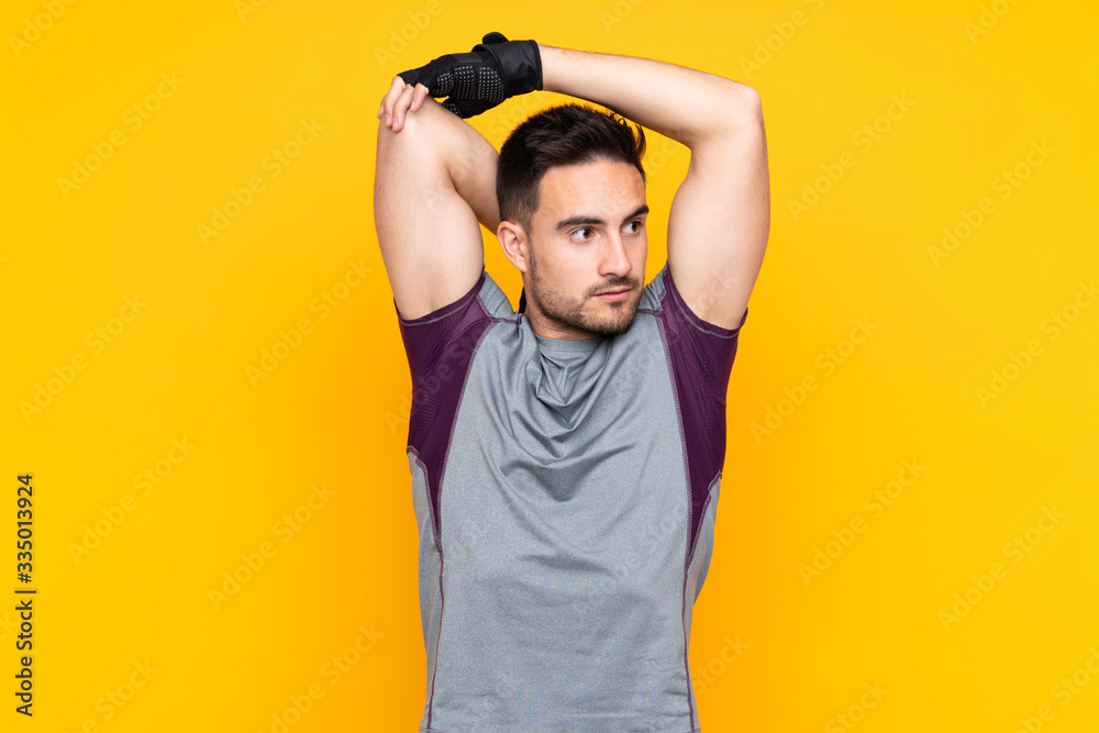 Sport man over isolated yellow wall stretching arm Sport man over isolated yellow wall stretching arm