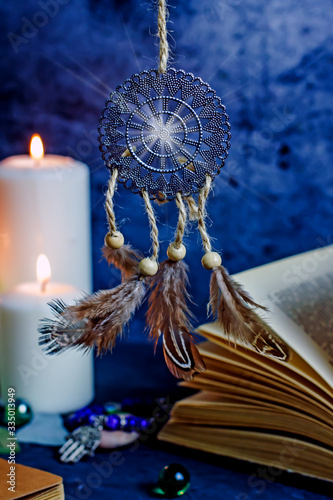 Dreamcatcher amulet feng shui. Dream catcher from metal and feathers against the background of burning candles. Background concept about magic, sorcery, esotericism, feng shui symbol