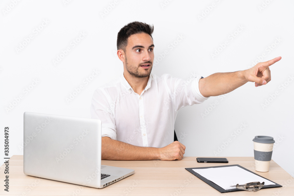 Young business man with a mobile phone in a workplace pointing away Young business man with a mobile phone in a workplace pointing away