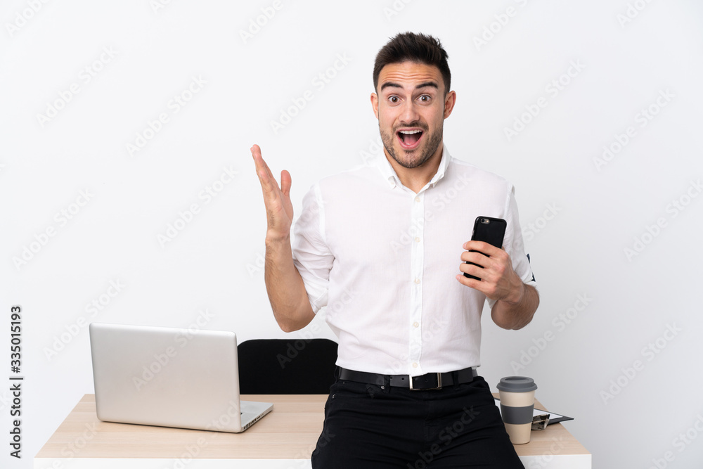 Young business man with a mobile phone in a workplace with surprise facial expression Young business man with a mobile phone in a workplace with surprise facial expression