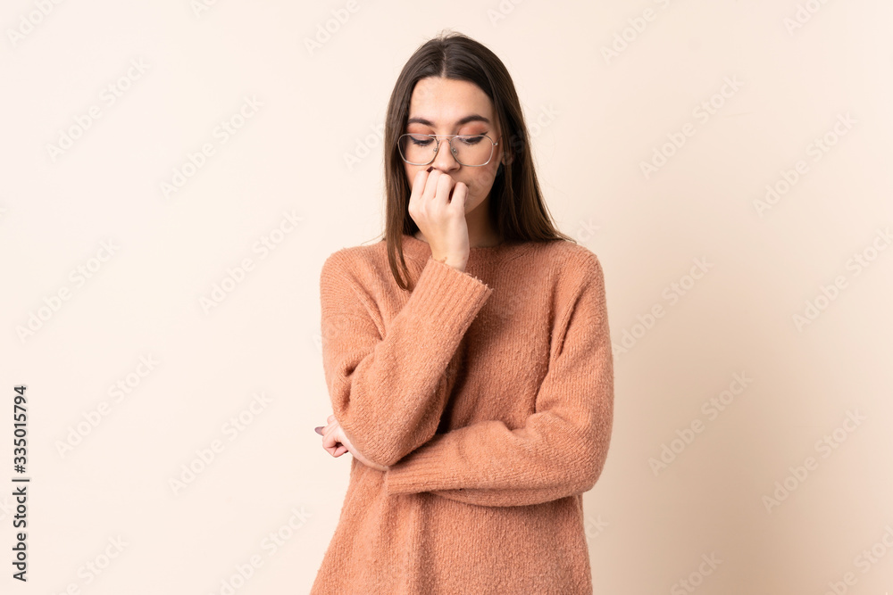 Young woman over isolated beige background having doubts Young woman over isolated beige background having doubts