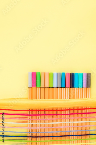Set of multicolored capillary pens of pastel colors on yellow background. © lusyaya