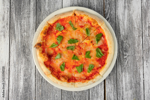 Pizza with tomato sauce and basil on wooden background. Top view, close-up