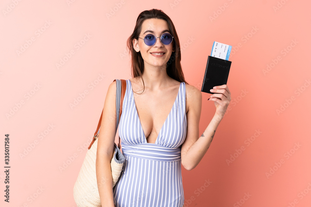Young woman in swimsuit in summer holidays holding a passport over isolated pink background with happy expression Young woman in swimsuit in summer holidays holding a passport over isolated pink background with happy expression