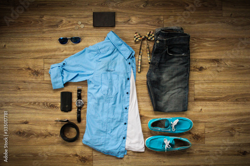 Top view of set of casual mens clothes and accessories on brown wooden background. Flat lay.