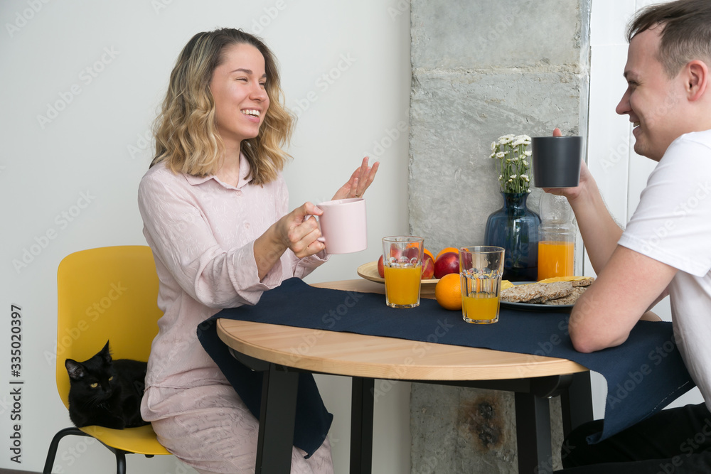 Couple eating breakfast early in the morning in the kitchen and having a good time.
