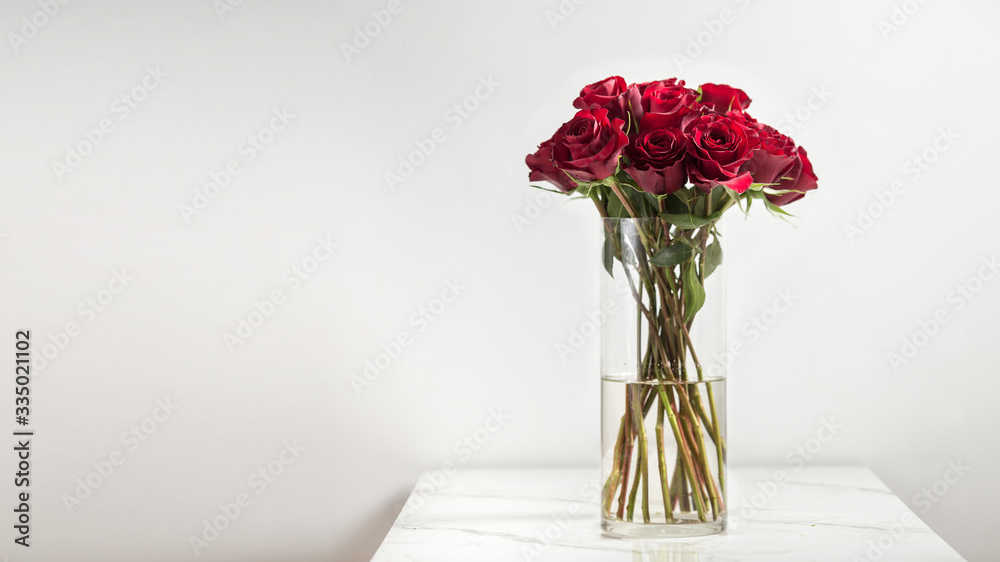 Fototapeta premium Beautiful dark red roses, flowers in a vase, side view, vertical, white background