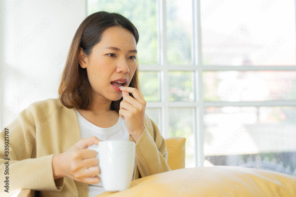 close up young asian woman take medicine pill wit warm water in glass at living room to relief fever and cold symptoms for lifestyle concept close up young asian woman take medicine pill wit warm water in glass at living room to relief fever and cold symptoms for lifestyle concept