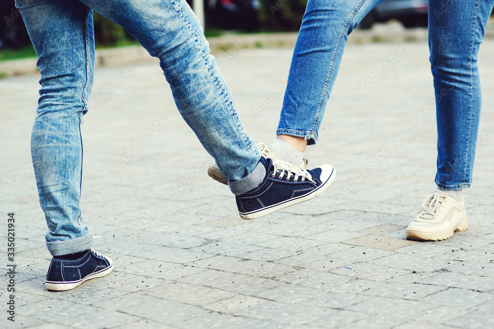 Girl and guy bump feet outdoors. Coronavirus epidemic. Foot shake style of greetings. Coronavirus prevention.