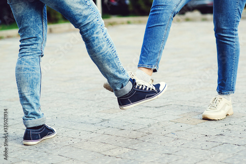 Girl and guy bump feet outdoors. Coronavirus epidemic. Foot shake style of greetings. Coronavirus prevention.