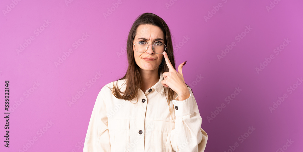 Young woman over isolated purple background showing something