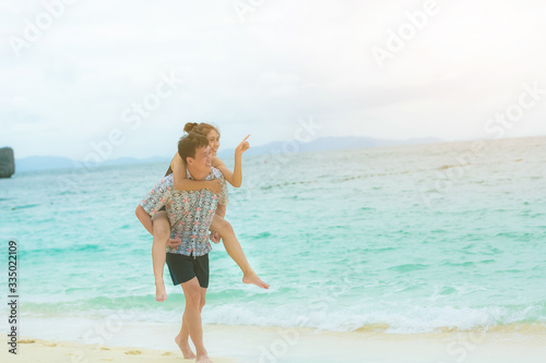 Happy young asian couple having fun at beach on sunny day.
