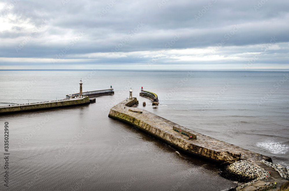 A view of Whitby harbour showing the lighthouse and entrance to the fishing port as seen from above.