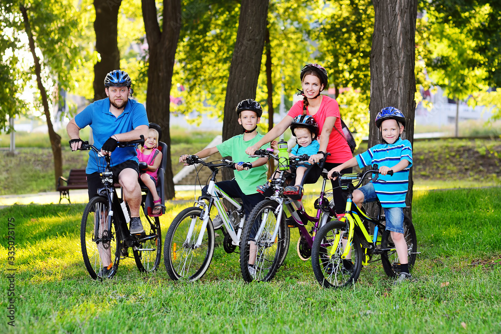 a group of people on bicycles - two adults and four young children in Bicycle gear and helmets against the background of trees, Park and green grass. Family and active lifestyle. a group of people on bicycles - two adults and four young children in Bicycle gear and helmets against the background of trees, Park and green grass. Family and active lifestyle.
