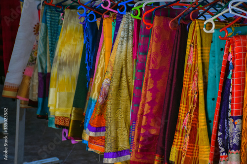 Collection of colorful sarees hanging in hangers in Indian shop