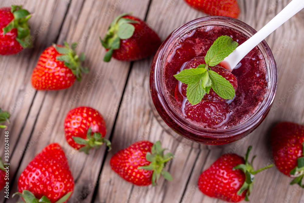 Homemade delicious strawberry jam and strawberry on a rustic wooden table Homemade delicious strawberry jam and strawberry on a rustic wooden table