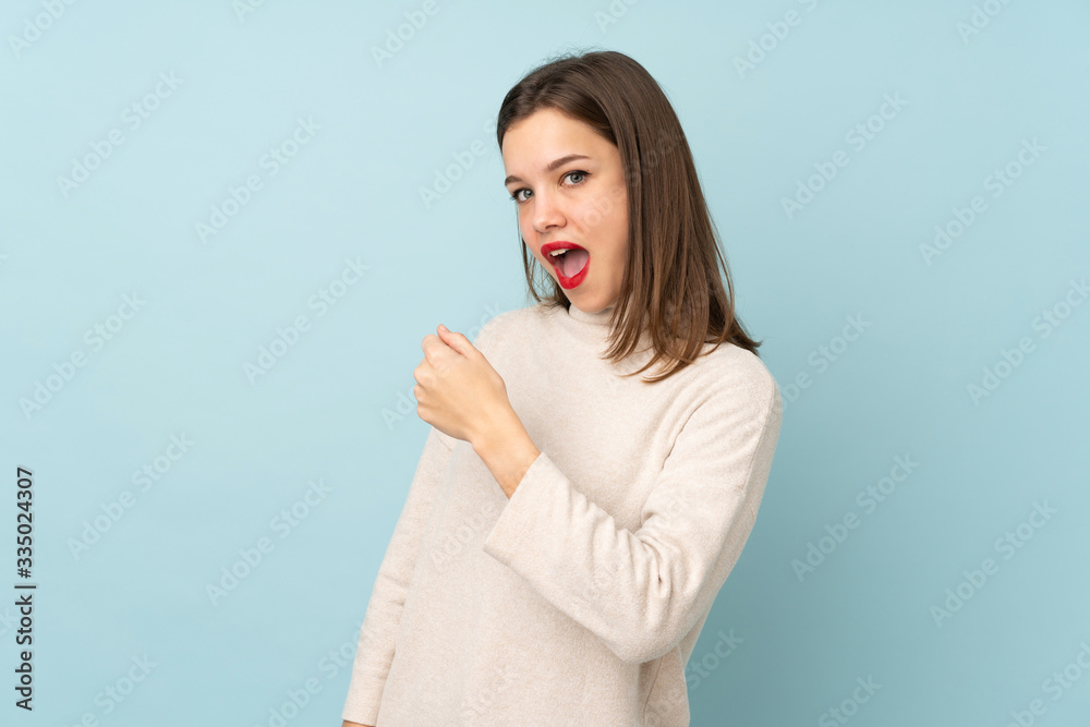 Teenager girl isolated on blue background celebrating a victory Teenager girl isolated on blue background celebrating a victory