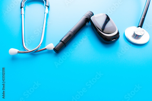 Medicine, Diabetes, Glycemia, Health care and people concept - close up of lancelet, Glucose meter and stethoscope on gray background. photo