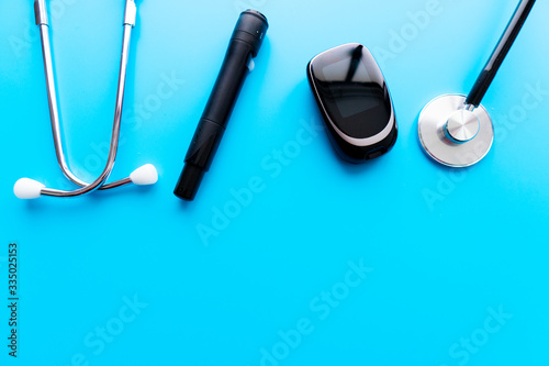 Medicine, Diabetes, Glycemia, Health care and people concept - close up of lancelet, Glucose meter and stethoscope on gray background. photo