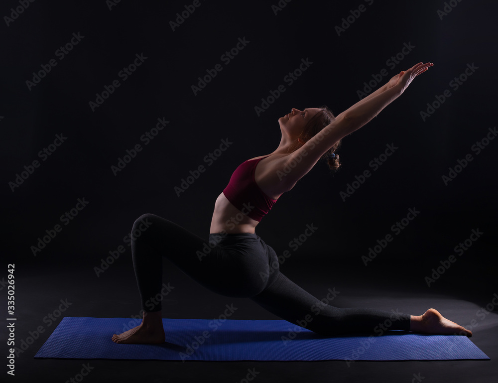 Photo of young sport woman doing yoga on mat over dark background Photo of young sport woman doing yoga on mat over dark background