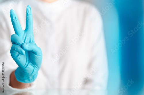hand gesture of doctor wearing blue gloves, sign for fighting