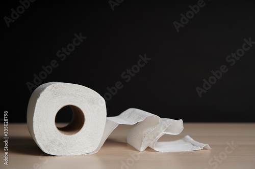A soft hygienic toilet paper on wooden table on black background