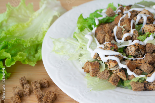 Classic Caesar salad with its ingredients: grilled chicken, croutons, lettuce and dressing sauce