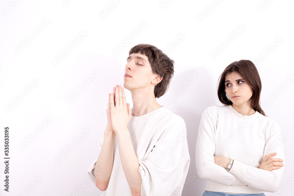 The young boy in a white sweatshirt is looking at the sky. He is praying and keeps his hands folded in the pray. The young girl stands next to him. The young boy in a white sweatshirt is looking at the sky. He is praying and keeps his hands folded in the pray. The young girl stands next to him.