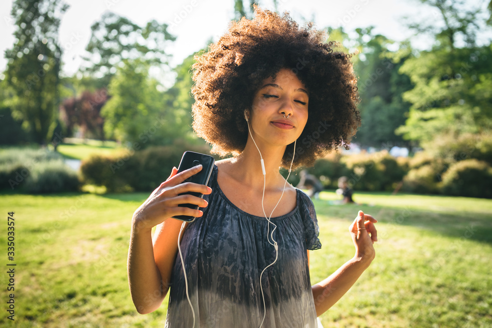 Φωτογραφία Young black woman dancing listening to the music with earphones from the smart p