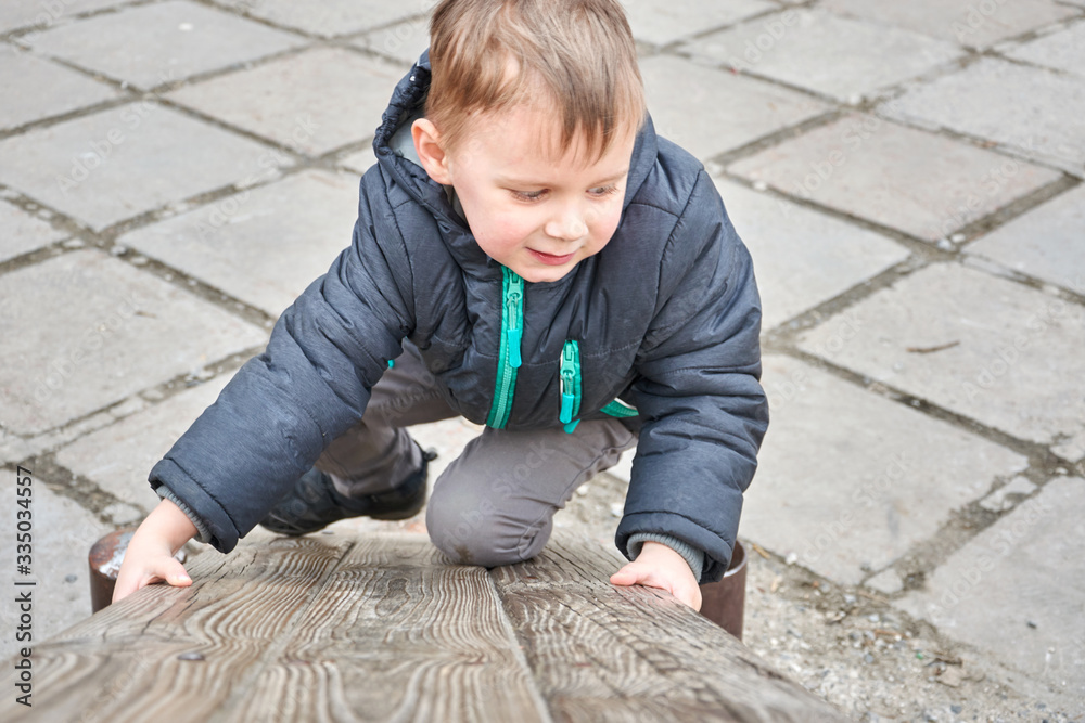 little boy is climbing on a wooden board. little boy is climbing on a wooden board.