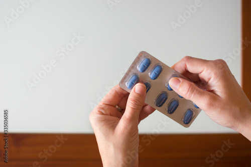 Female hand holding blue medical pills