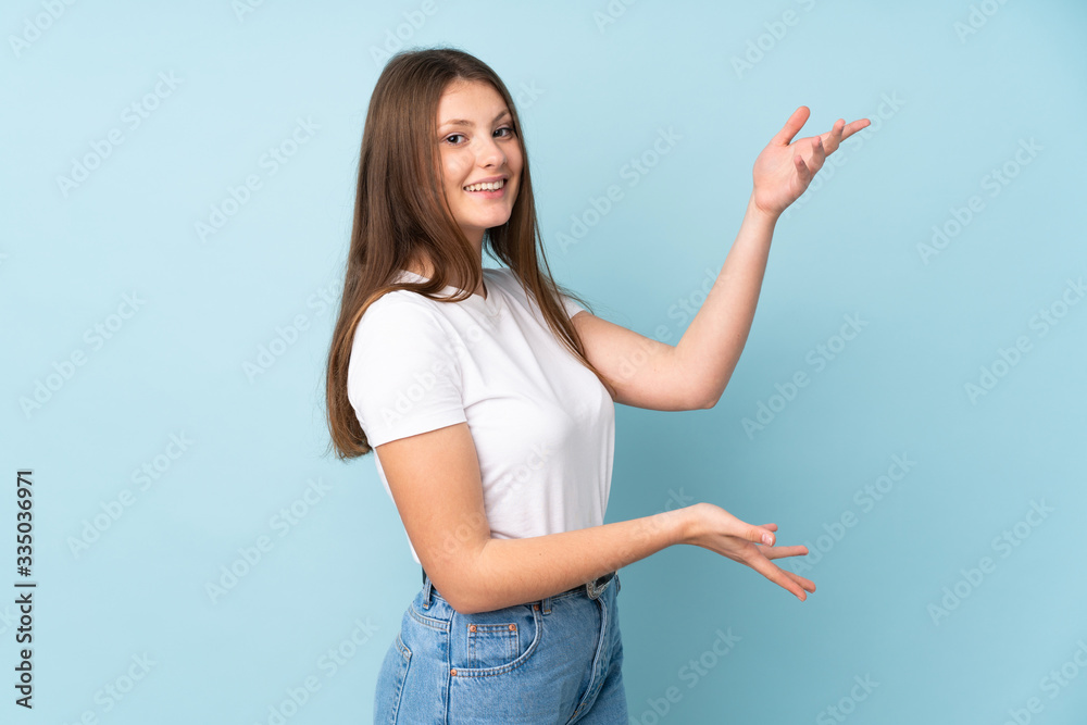 Teenager caucasian girl isolated on blue background extending hands to the side for inviting to come Teenager caucasian girl isolated on blue background extending hands to the side for inviting to come