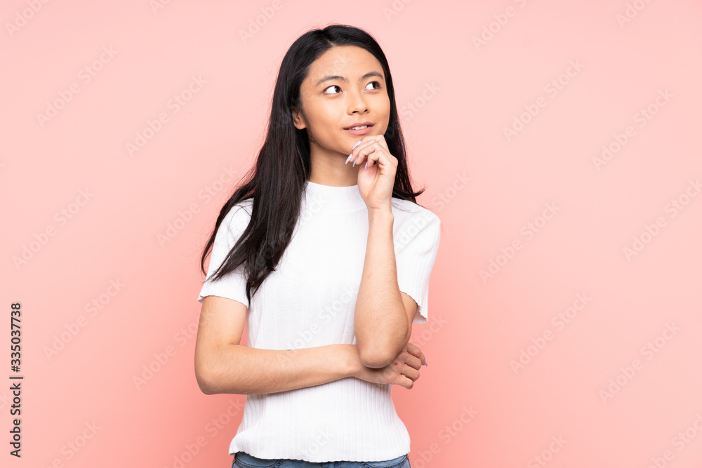 Teenager Chinese woman isolated on pink background thinking an idea while looking up Teenager Chinese woman isolated on pink background thinking an idea while looking up