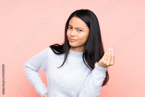 Teenager Chinese woman isolated on pink background making Italian gesture