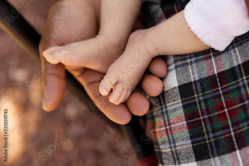 Father holding newborn daugther feet at summer sunset  family and parents concept