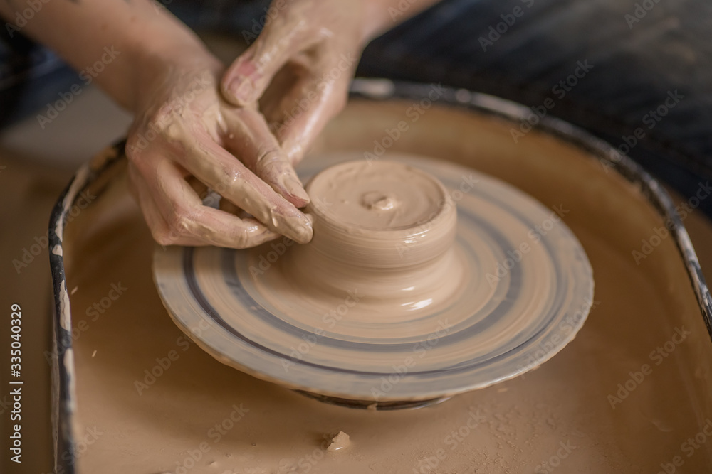 Workflow of a woman working behind a pottery wheel in an art workshop. Unknown master creates a jug. Focus only on the hands. Small business, talent, invention, inspiration concept. Workflow of a woman working behind a pottery wheel in an art workshop. Unknown master creates a jug. Focus only on the hands. Small business, talent, invention, inspiration concept.