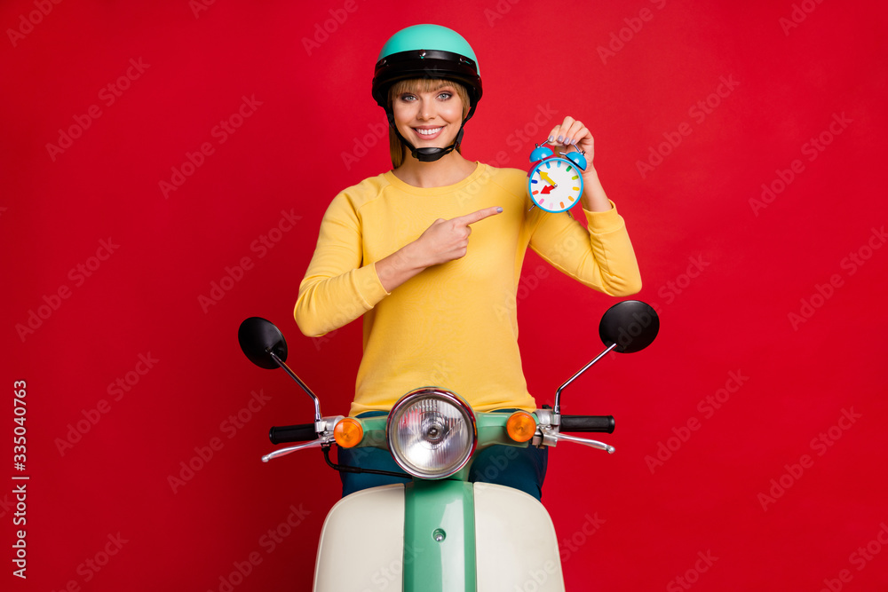 Positive sporty girl biker ride motorbike point index finger clock show her best time sport competition have deadline wear stylish trendy yellow sweater isolated bright shine color background