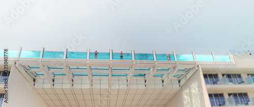 Fototapeta Naklejka Na Ścianę i Meble -  Hanging pool somewhere in South Europe. Tourists taking a swim during a hot day.