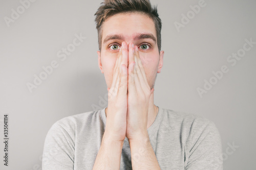 Young man sneezes in hand