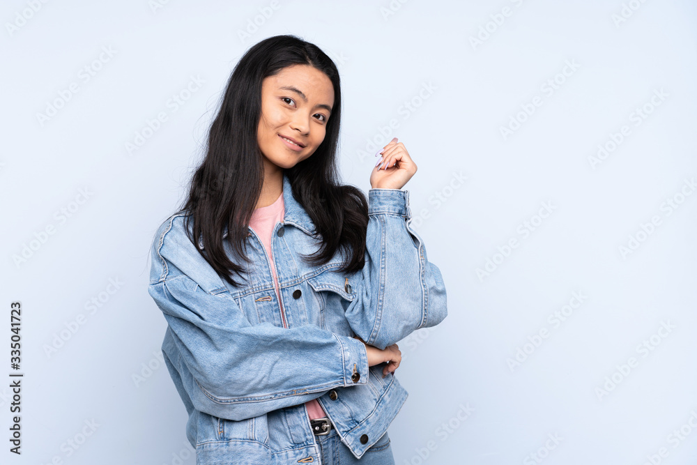 Teenager Chinese woman isolated on blue background happy and pointing up Teenager Chinese woman isolated on blue background happy and pointing up