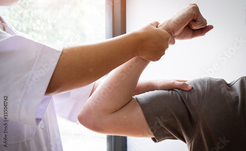Therapist treating test the strength of the biceps muscle of male patient.