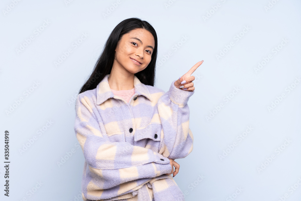 Teenager Chinese woman isolated on blue background pointing up a great idea Teenager Chinese woman isolated on blue background pointing up a great idea