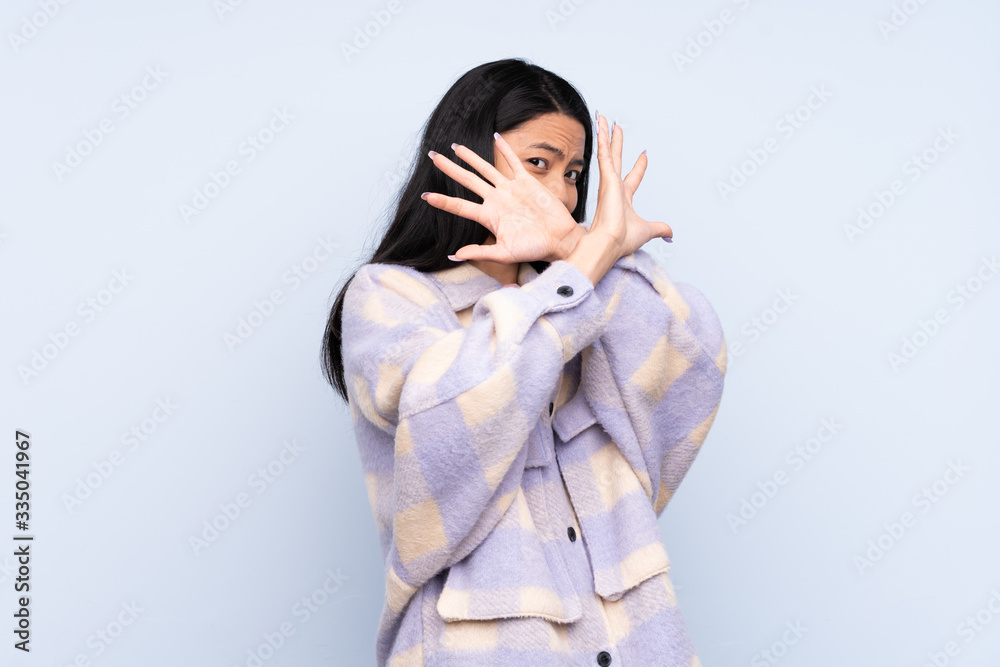Teenager Chinese woman isolated on blue background nervous stretching hands to the front Teenager Chinese woman isolated on blue background nervous stretching hands to the front