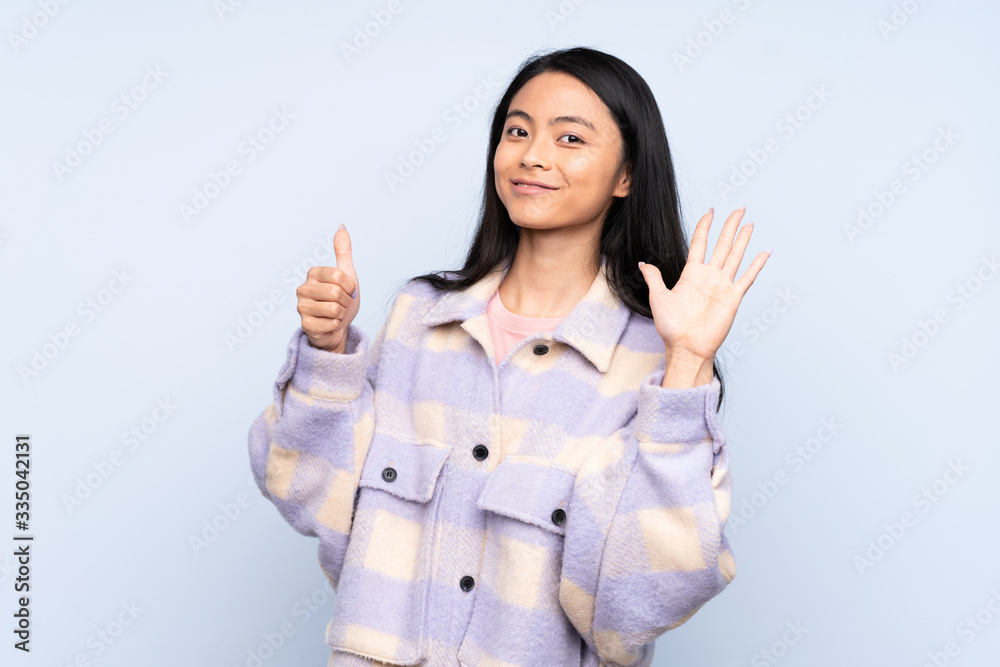 Teenager Chinese woman isolated on blue background counting six with fingers Teenager Chinese woman isolated on blue background counting six with fingers