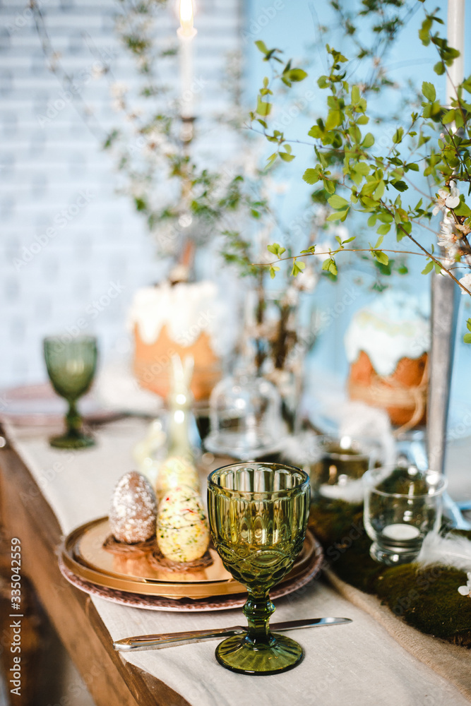 table decorated for Easter: Easter cakes, Easter eggs, Easter bunnies, flowering cherry branches in glass cups, plates and glasses table decorated for Easter: Easter cakes, Easter eggs, Easter bunnies, flowering cherry branches in glass cups, plates and glasses